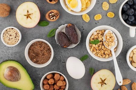 Ingredients for a healthy breakfast, nuts, oatmeal, flaxseed, dried fruit, avocado, egg, quinoa, cornflakes, berries, fruits, blueberry, almonds, walnuts. The concept of natural organic food in season. Top view,の写真素材