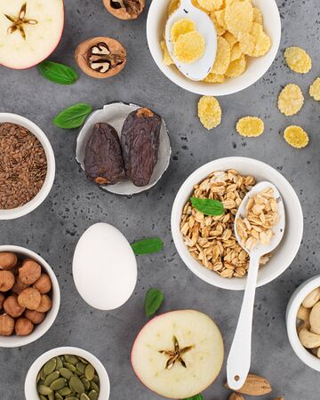 Ingredients for a healthy breakfast, nuts, oatmeal, flaxseed, dried fruit, avocado, egg, quinoa, cornflakes, berries, fruits, blueberry, almonds walnuts The concept of natural organic food in season Top viewの写真素材