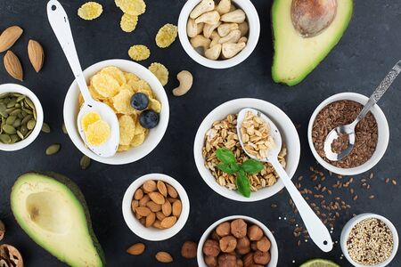 Ingredients for a healthy breakfast, nuts, oatmeal, flaxseed, dried fruit, avocado, egg, quinoa, cornflakes, berries, fruits, blueberry, almonds walnuts The concept of natural organic food in season Top viewの写真素材