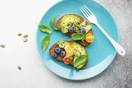 Healthy balanced nutrition. Open sandwiches on whole wheat dark bread with avocado, celery,...