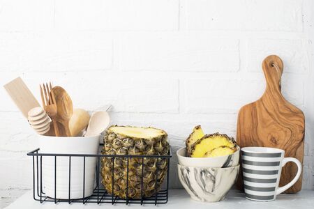 Kitchen shelf lifestyle white background with fresh lemons, pineapple, kitchen tools, appliances, chopping boards, storage baskets. Eco-friendly life. Home style, minimalism, healthy eatingの写真素材