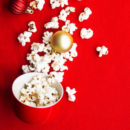 Homemade popcorn for a festive treat in red Christmas mugs with shiny New Years red and gold Christmas decorations balls. Top view. Festive atmosphere picture. Top view,の写真素材