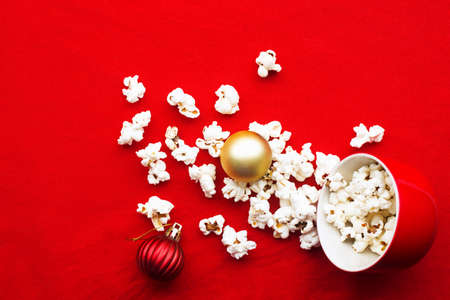 Homemade popcorn for a festive treat in red Christmas mugs with shiny New Years red and gold Christmas decorations balls. Top view. Festive atmosphere picture. Top view,の写真素材
