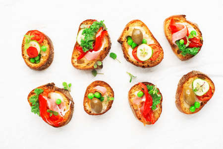 Finger food. Appetizing crostini with baked capsicum, green peas, bacon, kale and lettuce as a festive snack. Top view,の写真素材
