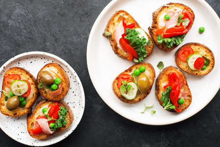 Finger food. Appetizing crostini with baked capsicum, green peas, bacon, kale and lettuce as a festive snack. Top view,の写真素材