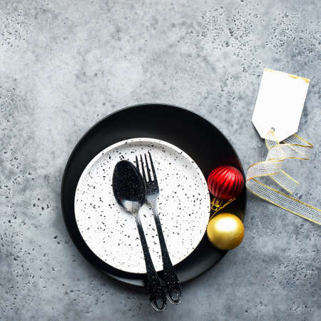 Christmas table set minimalism style in black and red on a plain gray background with black cutlery. Top view.,の写真素材