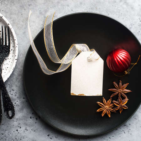 Christmas table set minimalism style in black and red on a plain gray background with black cutlery. Top view.,の写真素材