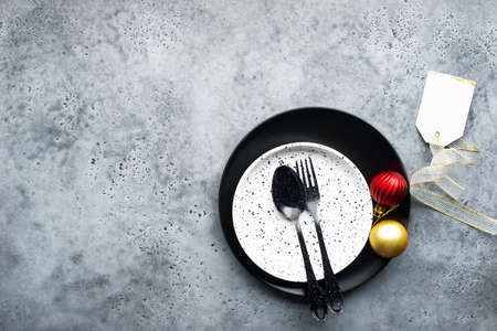 Christmas table set minimalism style in black and red on a plain gray background with black cutlery. Top view.,の写真素材