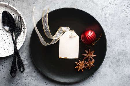 Christmas table set minimalism style in black and red on a plain gray background with black cutlery. Top view.,の写真素材