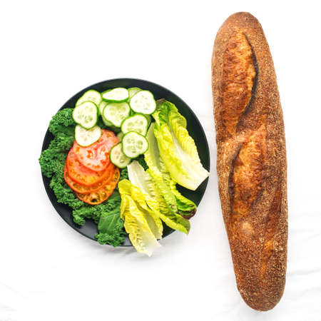 Fresh baguette and vegetable slices, tomatoes, cucumber, romano lettuce leaves, mushrooms for making sandwiches for a snack. Simple homemade comfort food. Top view,の写真素材