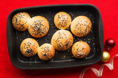Dinner rolls Christmas New Year. Bread portioned in a baking dish on a red festive background with Christmas balls decor. Traditional colors and foodの写真素材