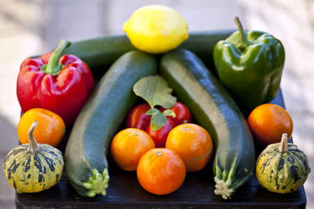 Group of fresh fruits  mandarines, tangerines, clementines, lemons and vegetables  broccoli, courgettes, radish, paprica and tomatoes on a wooden tableの写真素材