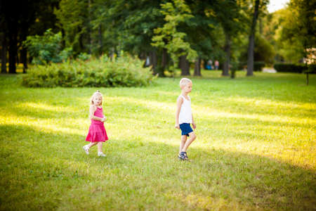 Little children walking through park during beautiful summer eveningの写真素材