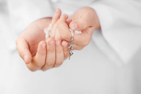 First Holy Communion concept - close up on rosary on child's handsの写真素材
