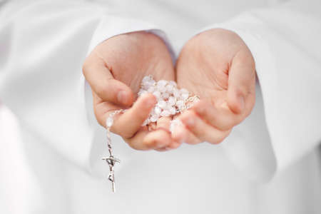 First Holy Communion concept - close up on rosary on child's handsの写真素材