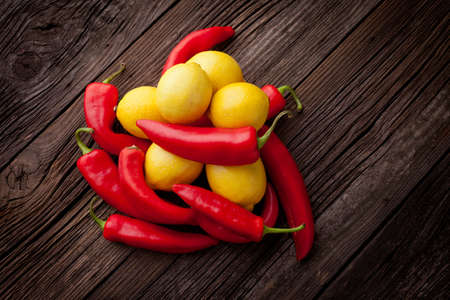 Group of fresh red hot chilli peppers and yellow lemons on an old vintage wooden tableの写真素材
