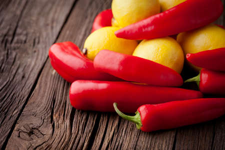 Group of fresh red hot chilli peppers and yellow lemons on an old vintage wooden tableの写真素材