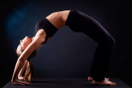 Young woman practicing yoga. Studio, black background shotの写真素材