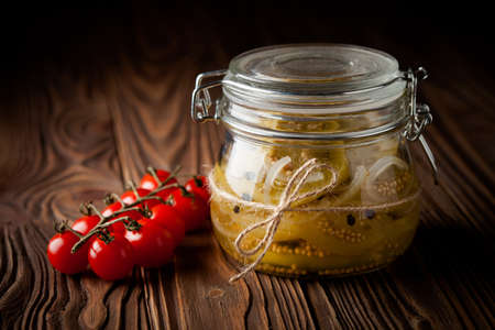 Homemade DIY natural marinated green tomatoes in a jar on wooden tableの写真素材