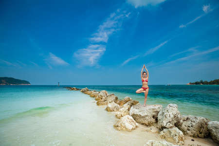 Hot summer yoga session on a beach - tropical Koh Phangan island, Thailand. Vriksha-asana - tree pose.の写真素材