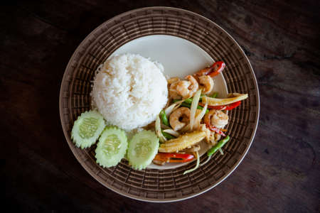 Stir fried prawns, red hot chilli pepper, babycorn, onion, bean served with cucumber and rice. Traditional thai cuisine.の写真素材