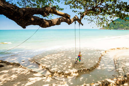 Summer seascape on tropical island Koh Phangan in Thailand - Bottle beach. Young woman on swing.の写真素材