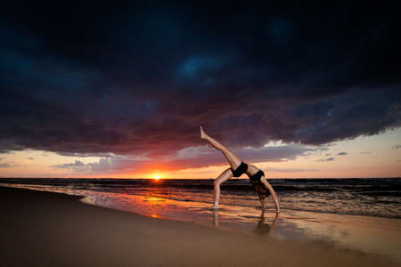 Summer yoga session on a beautiful golden beach - polish Grzybowo village, near to Kolobrzeg. Chakra-asana, wheel poseの写真素材