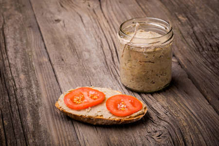 Homemade DIY natural vegan very healthy green lentil paste with rye bread and tomatoes in a glass jar on a wooden tableの写真素材
