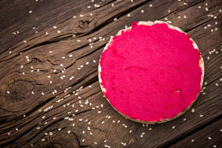 Homemade DIY natural vegan very healthy pink hummus of chickpeas and beetroot with rice wafle and in a glass jar on a wooden tableの写真素材