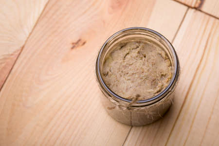 Homemade DIY natural vegan very healthy green lentil paste in a glass jar on a wooden tableの写真素材