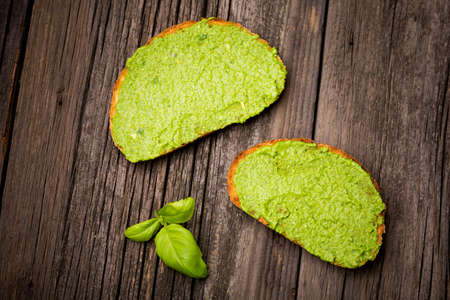 Natural homemade DIY vegan very healthy green pesto made of rocket, basil and pini nuts in a glass jar on a wooden tableの写真素材