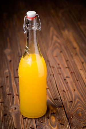 Homemade DIY natural healthy orange with cloves liqueur in glass bottle on a wooden tableの写真素材