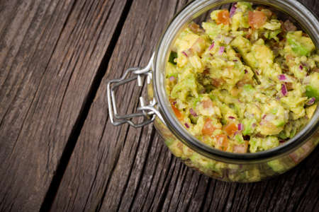 Homemade DIY natural mexican guacamole made of avocado, red onion, tomatoes, garlic, lime juice and fresh corianderの写真素材