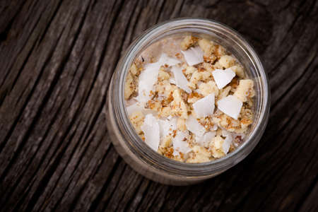 Homemade DIY natural healthy dessert made from kefir (polish - grzybek tybetanski), bananas, carob, chia seeds, rye and coconut flakes, walnuts on a wooden tableの写真素材