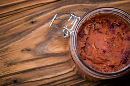 Homemade DIY natural vegan very healthy red bean paste in a glass jar on a wooden table with breadの写真素材