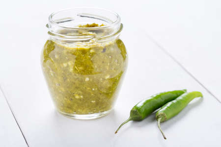 Homemade DIY natural extra hot kenya chilli sauce in a glass jar on wooden tableの写真素材