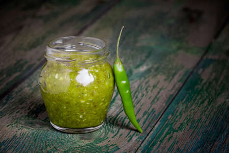 Homemade DIY natural extra hot kenya chilli sauce in a glass jar on wooden tableの写真素材