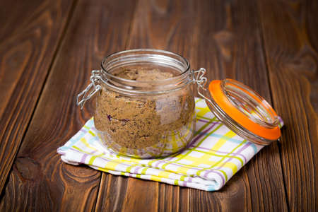 Homemade DIY natural vegan very healthy black bean paste with garlic, onion, coriander and lime in a glass jar on a wooden tableの写真素材
