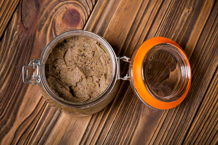 Homemade DIY natural vegan very healthy black bean paste with garlic, onion, coriander and lime in a glass jar on a wooden tableの写真素材