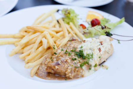 Delicious grilled chicken breast in blue cheese sauce, potato fries and salad served in local restaurant in Frydek Mistek. Moravian food specialities.の写真素材