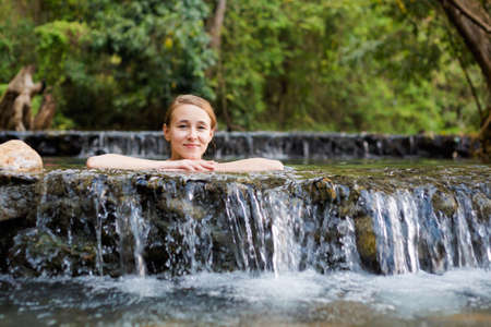 Young caucasian beautiful woman tourist enjoying a bath in Pai Sai Ngam secret hotsprings hidden in jungle in north Thailand. Landscape with men and nature in south east asia during summer.の写真素材