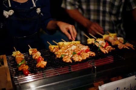 Preparing asian hot skewers satay made of chicken, pork, beef, pineapple, tomato, pepper and onion. Traditional thai streetfood cuisine made of fresh ingredients.の写真素材
