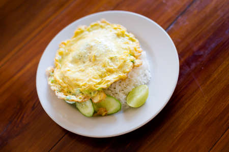 Fresh prepared asian fried egg omlette on jasmine rice served with lime and cucumber slices. Traditional thai cuisine made of fresh ingredients.の写真素材