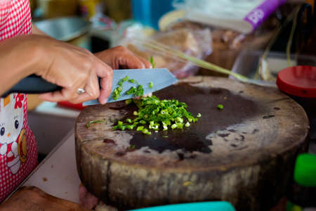 Traditional way of preparing vegetable slices using chopper knife. Picture of making traditional thai cuisine made of fresh ingredients.の写真素材