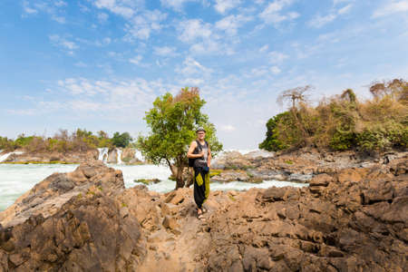 Young caucasian man on Big Khone Phapheng waterfall - don phapheng, don khong, si phan don on four thousand islands in Laos. Landscape of nature in south east asia during summer.の写真素材
