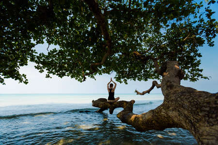 Summer sunrise yoga session on beautiful White Sand  beach - tropical koh Chang island in Thailand. Meditation - namaste lotus pose - padma asana
の写真素材