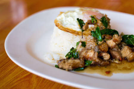 Fresh prepared asian crispy pork slices with holy basil served with steamed jasmin rice and egg. Traditional thai cuisine made of fresh ingredients.の写真素材