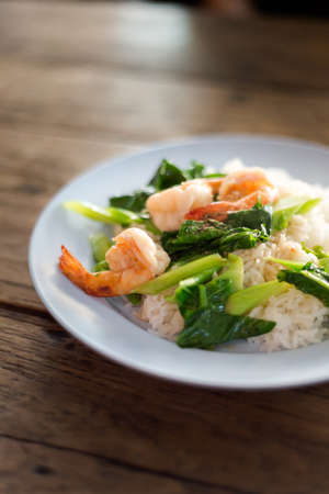 Thai fried kale with shrimps served on steamed rice. Traditional south east asian cuisine.