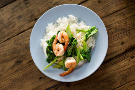 Thai fried kale with shrimps served on steamed rice. Traditional south east asian cuisine.