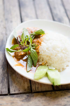Fresh prepared asian pork chunks in red curry sauce with holy basil served with steamed jasmine rice. Traditional thai cuisine made of fresh ingredientsの写真素材
